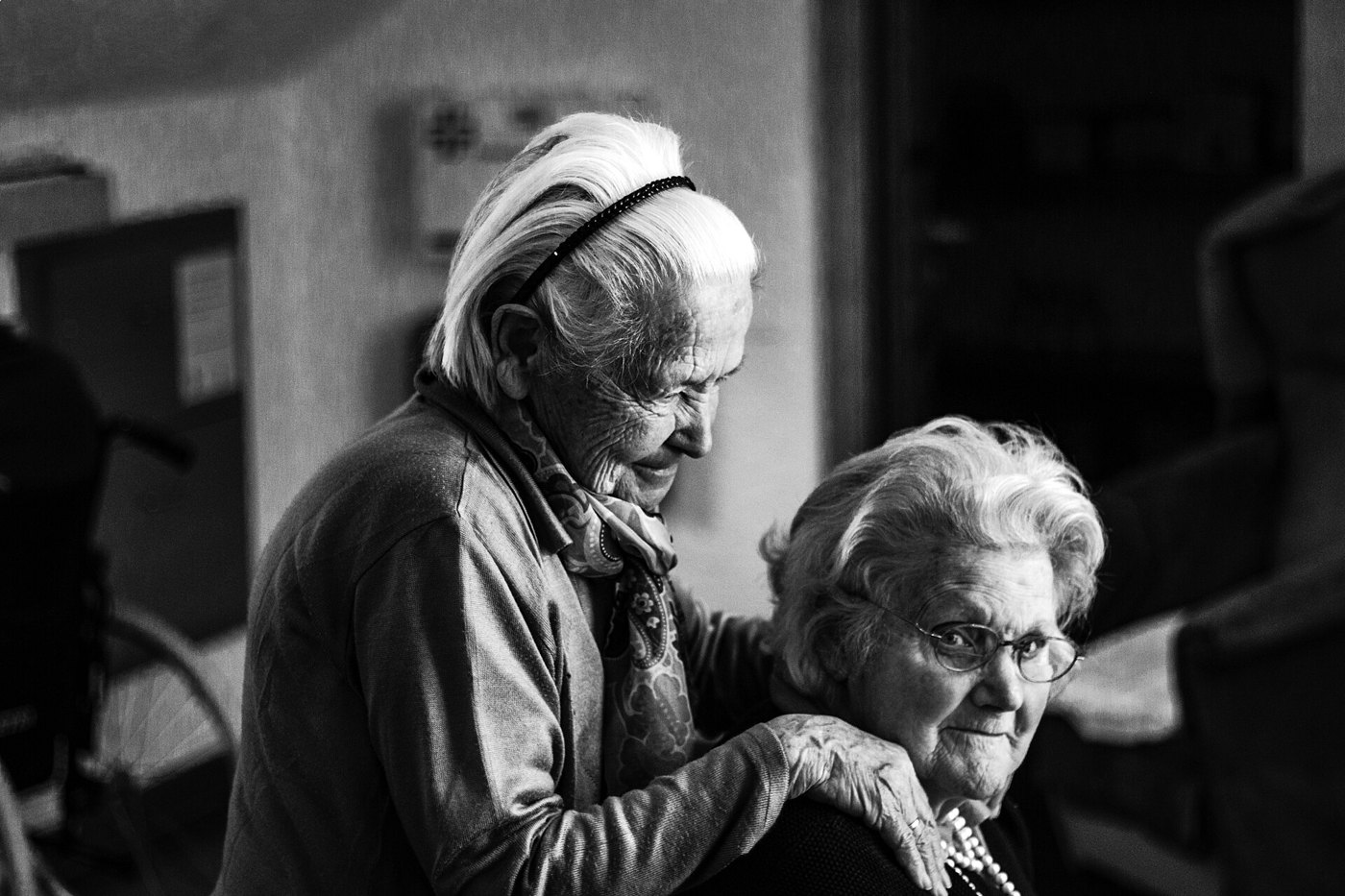 Una donna anziana appoggia le mani sulle spalle di un’amica